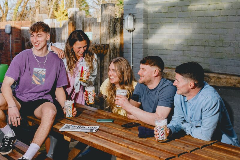 A group of young adults sat round a table outside
